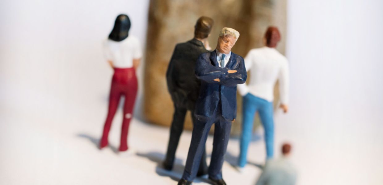 (© Veit Mette) Miniaturfigur in Chefpose im Hintergrund weitere Miniatur-Personen alle mit dem Rücken zum Chef auf einen Stein blickend