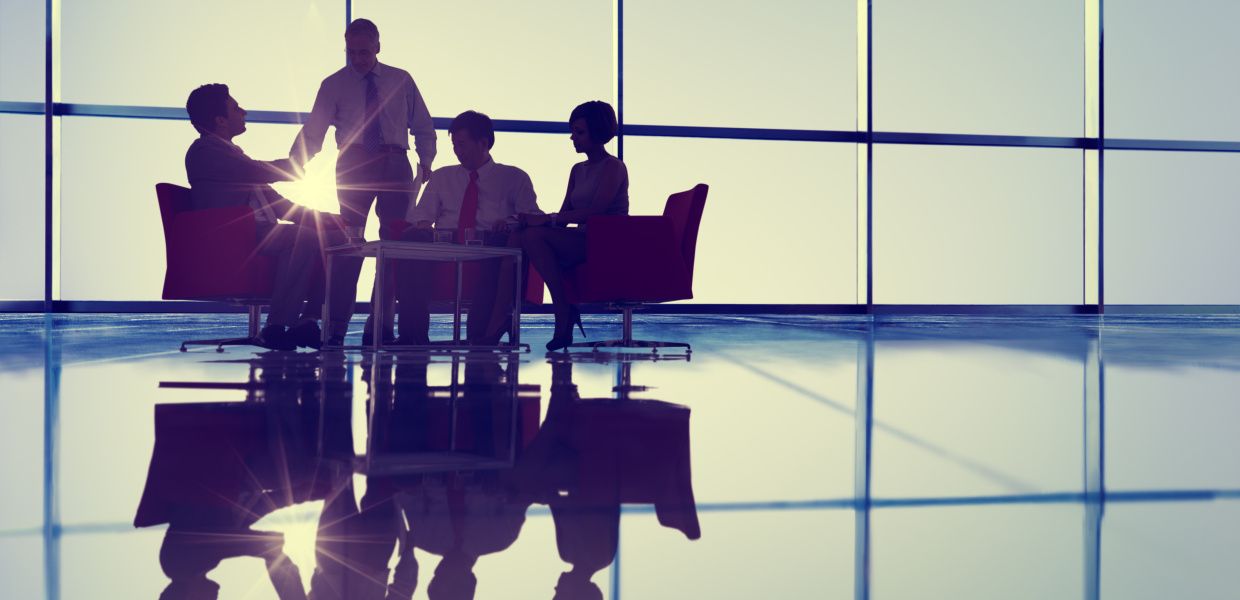 (© Shutterstock / Rawpixel.com) Personen in einer Sitzgruppe im Gegenlicht vor einer Glassfassade